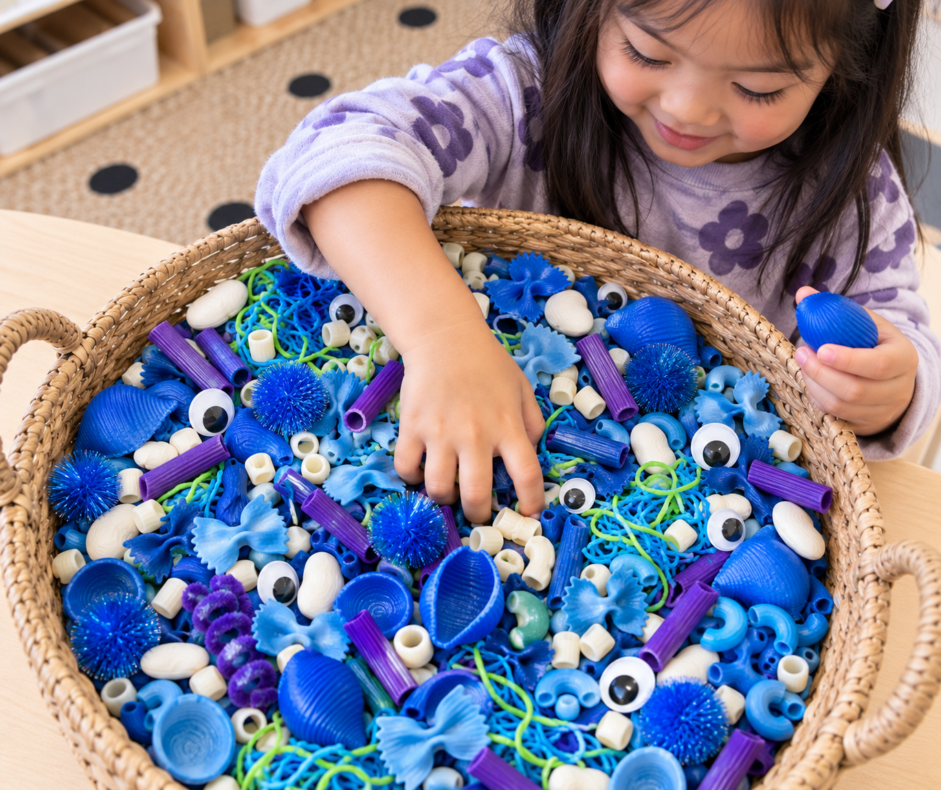 Preschool child exploring a monster-themed pasta sensory bin